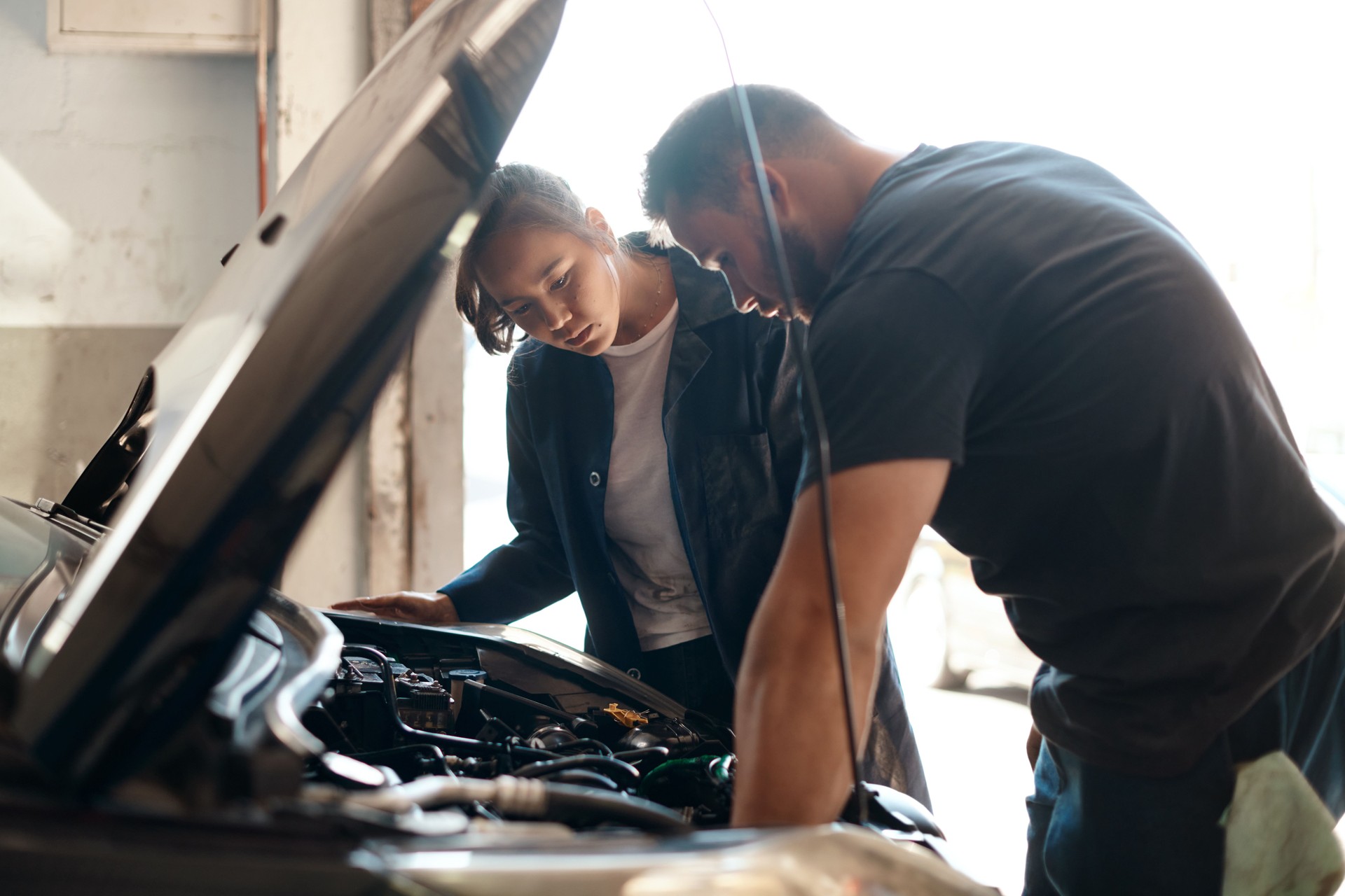 Photo de deux mécaniciens travaillant ensemble sur une voiture dans un atelier de réparation automobile