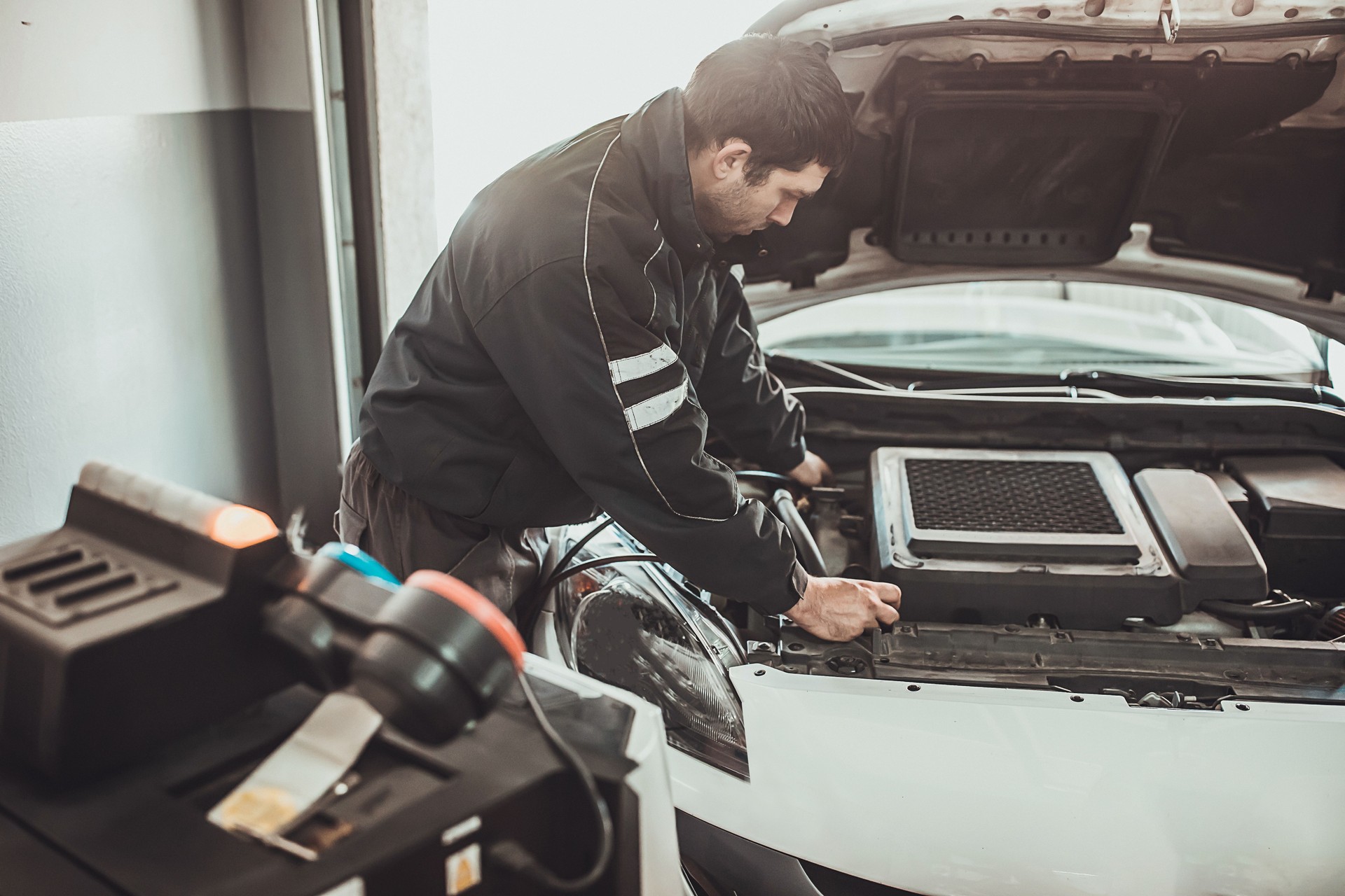 Mécanicien rechargeant l’air condition de voiture dans l’atelier de réparation d’automobile